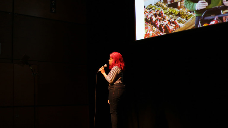 Nostalgia - CCA artist in front of large screen delivering a spoken performance