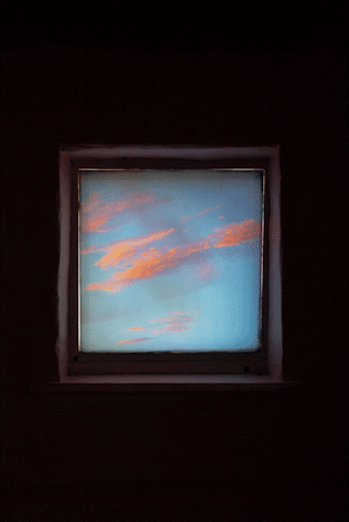 A square printed vinyll of blue sky and pink clouds, surrounded by dark wall.