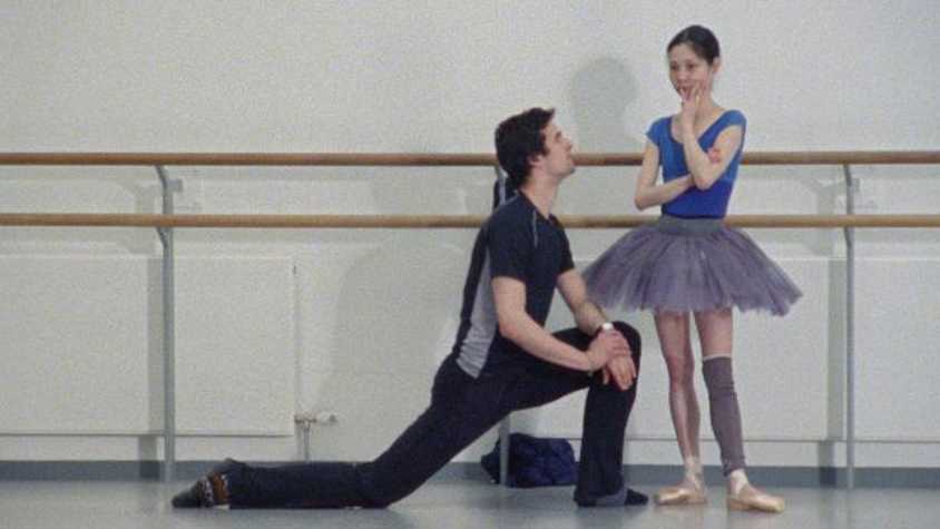film still of a male dancer knelt beside a female ballerina in a dance studio