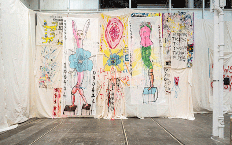 Fabric hanging from walls with colourful artwork painted onto it.