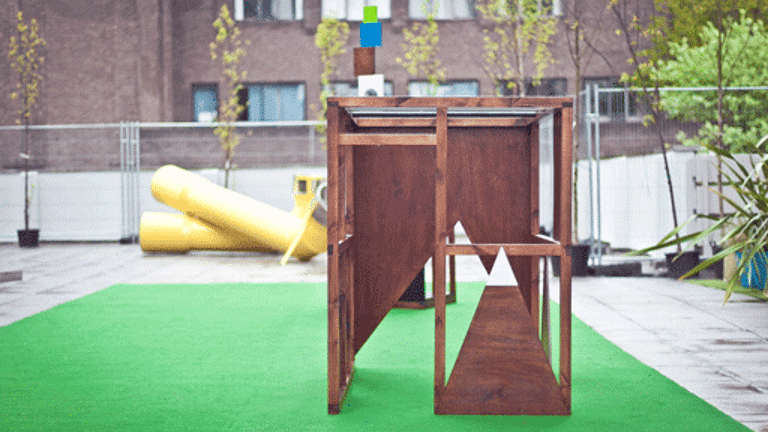 wooden geometric structure on a green rug in an outdoor space