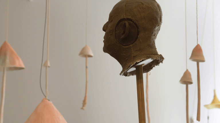 Sculptural head on stick, sculptural mushrooms suspended from ceiling, sound installation