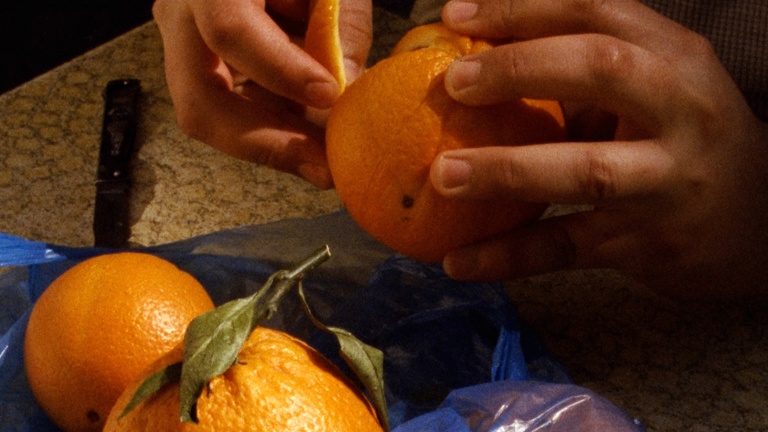 An image of oranges, and hands peeling them