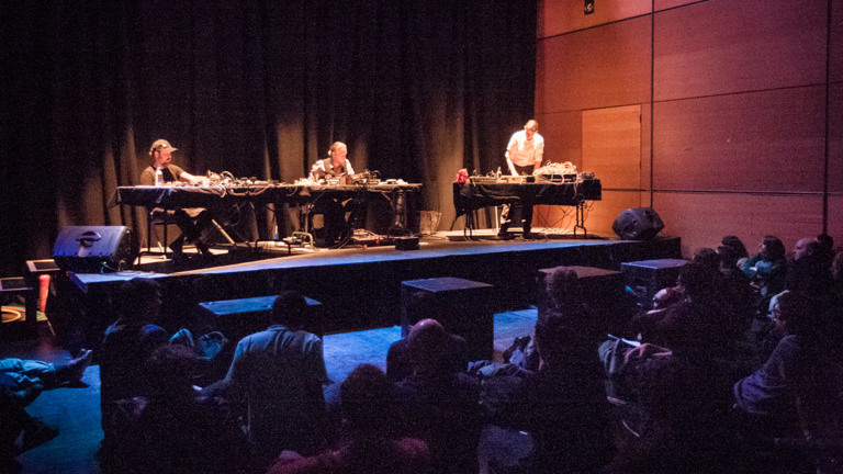 Counterflows : CCA musicians behind mixing desks on a stage in front of an audience