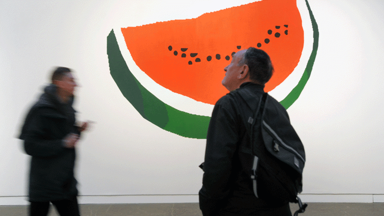  large painting of watermelon slice, with festival attendees viewing