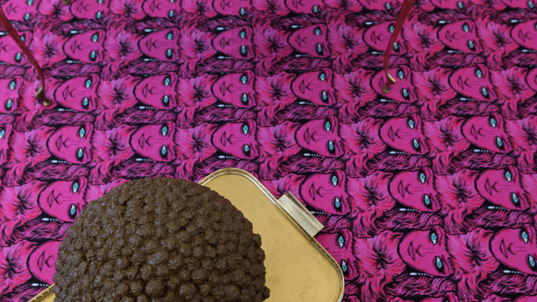 Patterned carpet of faces (repeating pattern) , sculptural object on a gold-coloured tray