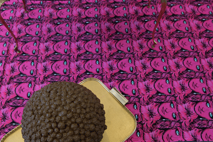 Patterned carpet of faces (repeating pattern) , sculptural object on a gold-coloured tray
