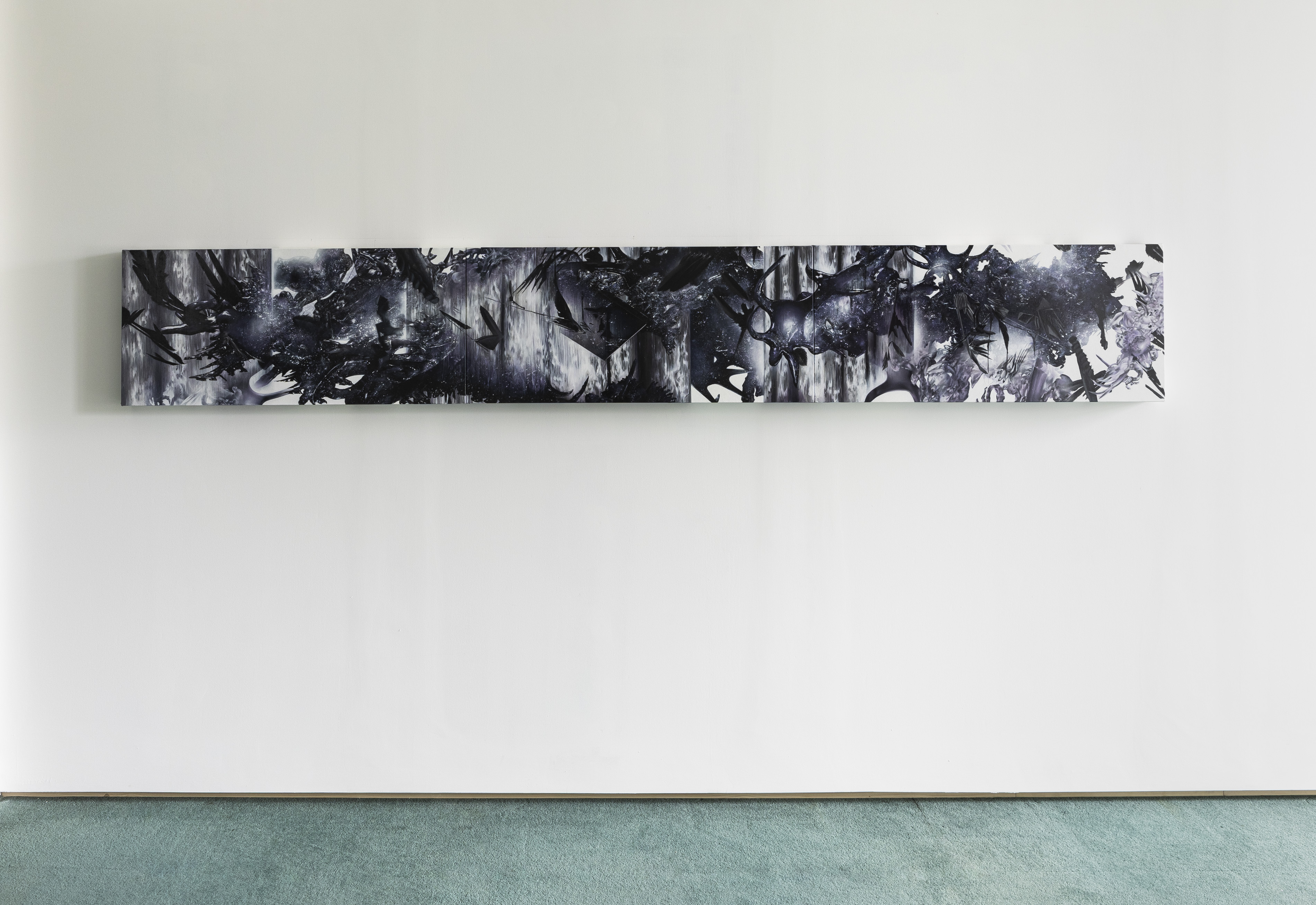 A long, narrow horizontal panel painting mounted on a white wall above green carpet. The composition is rendered in black, white and grey, with dense, layered abstract forms resembling birds in flight, antlers, and foliage against a streaked, atmospheric background.