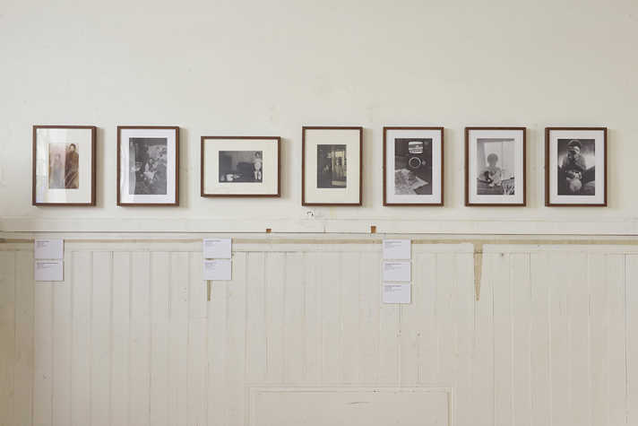 A row of framed photographs displayed on a white wall.