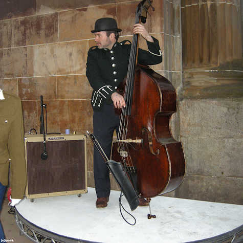 a person wearing a black uniform jacket playing a double bass