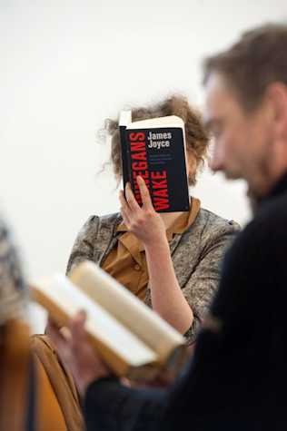 woman reading Finnegan's Wake by James Joyce. The book completely covers her face. In the foreground a man reads another book.